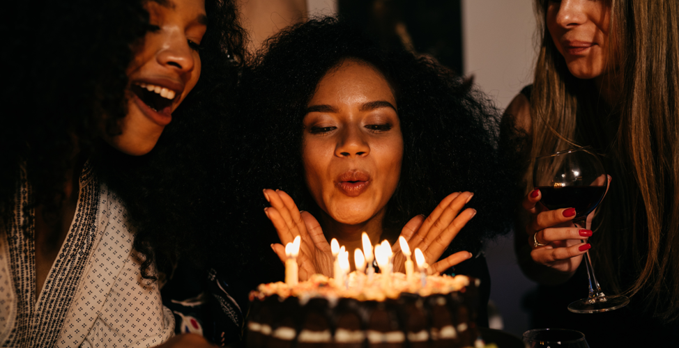 Lady Blowing Out Candles At Birthday Party